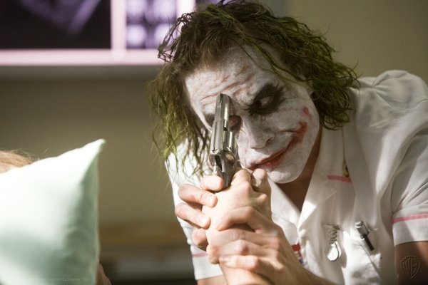 Joker keeping the gun's hammer down and holding Harvey's thumb